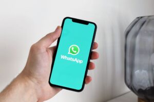 Pessoa segurando um celular com o aplicativo do WhatsApp aberto na tela para gerenciar duas contas no mesmo aparelho.